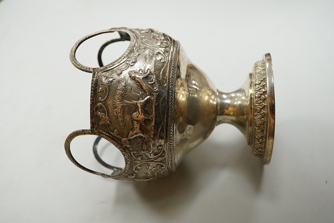 A late 19th/early 20th century Indian white metal pedestal bowl, with unusual ring handle border, embossed with continuous scene of wild animals, diameter 12.3cm, 6.3oz.
